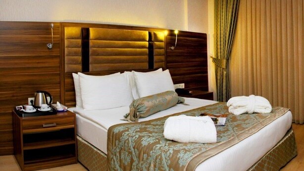 Hotelkamer met een groot bed, een houten bureau, een stoel, een flatscreen televisie en een nachtkastje met lamp en beker.