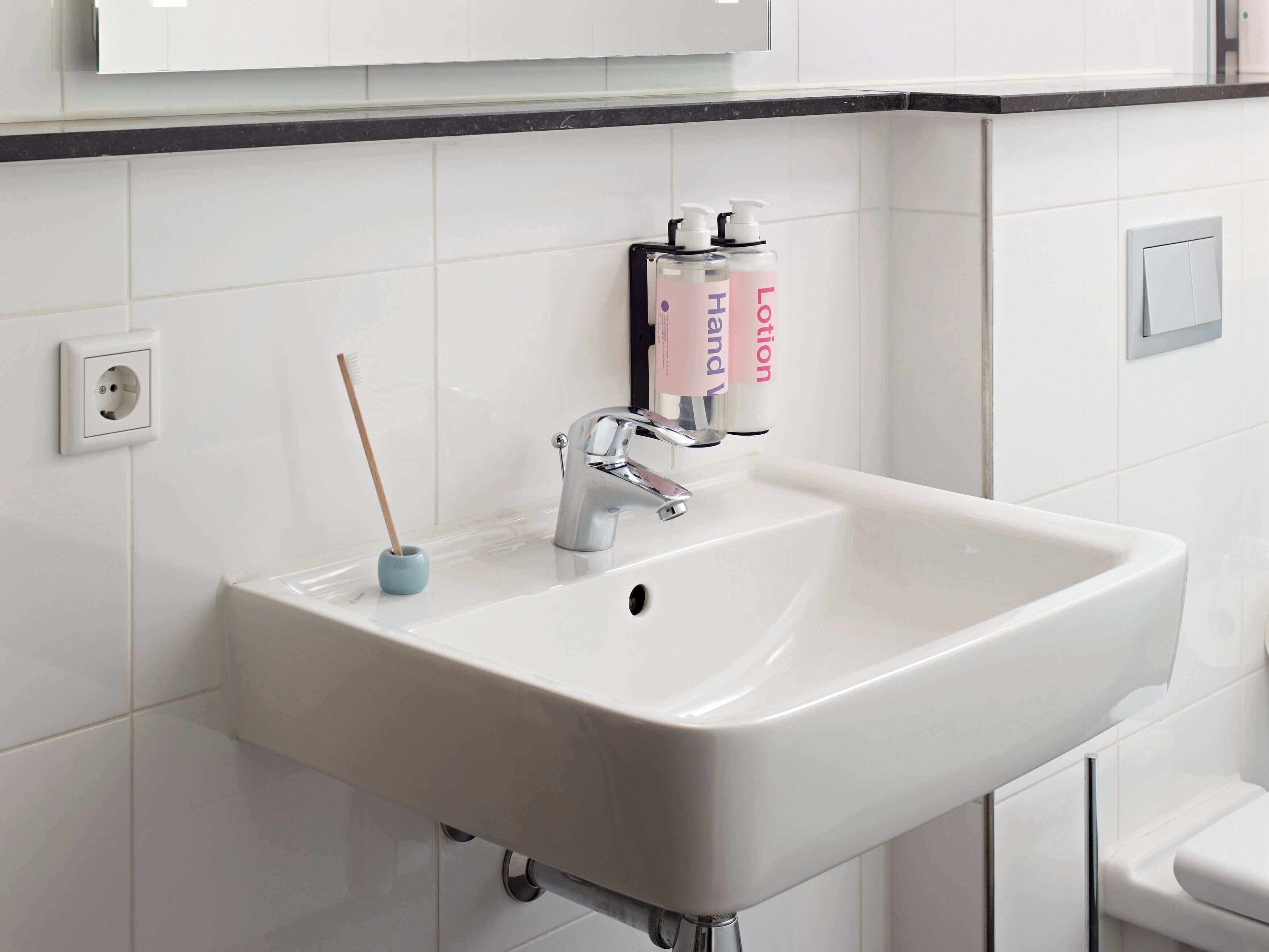 Un baño con lavamanos blanco, un espejo y artículos de aseo.