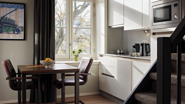 Eine kompakte Küche mit Mikrowelle, Kaffeemaschine und einem Fenster mit Blick auf Bäume.