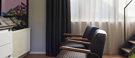 A modern living room with a black leather sofa, a white radiator, and a sign reading "Welcome to Numa".
