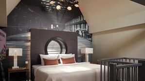 Ein Schlafzimmer mit einem großen Bett, einem runden Fenster und Blick auf ein Industriegebiet.