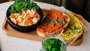 A meal consisting of salmon and scrambled eggs with spinach, and two types of bread with different spreads.