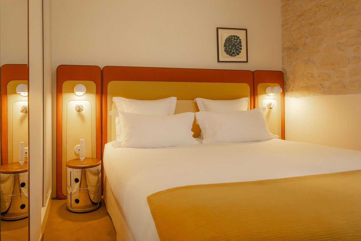 A hotel room with a large bed, two bedside tables, and a wall-mounted picture.
