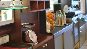 Een keuken met houten kastjes, een koffieapparaat en een schaal fruit.