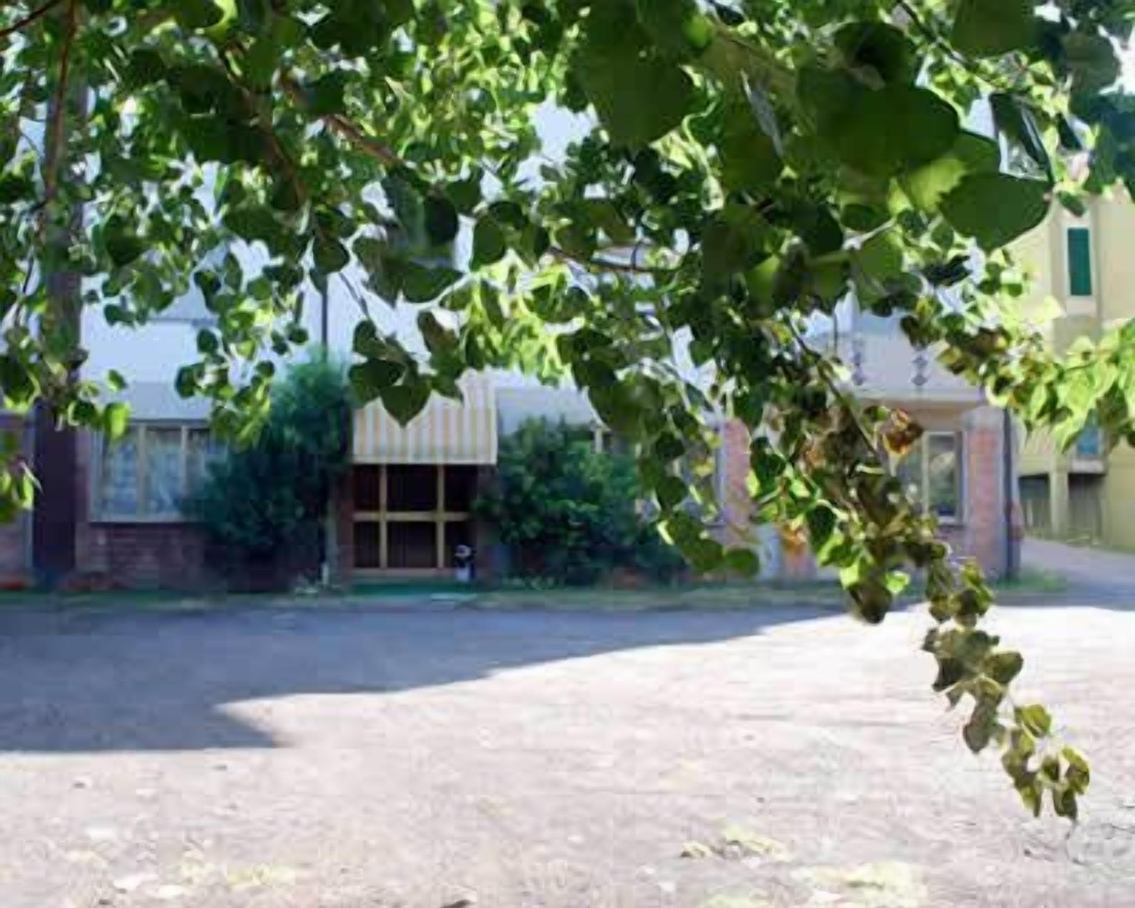 Un edificio con un amplio acceso de vidrio, rodeado de vegetación.