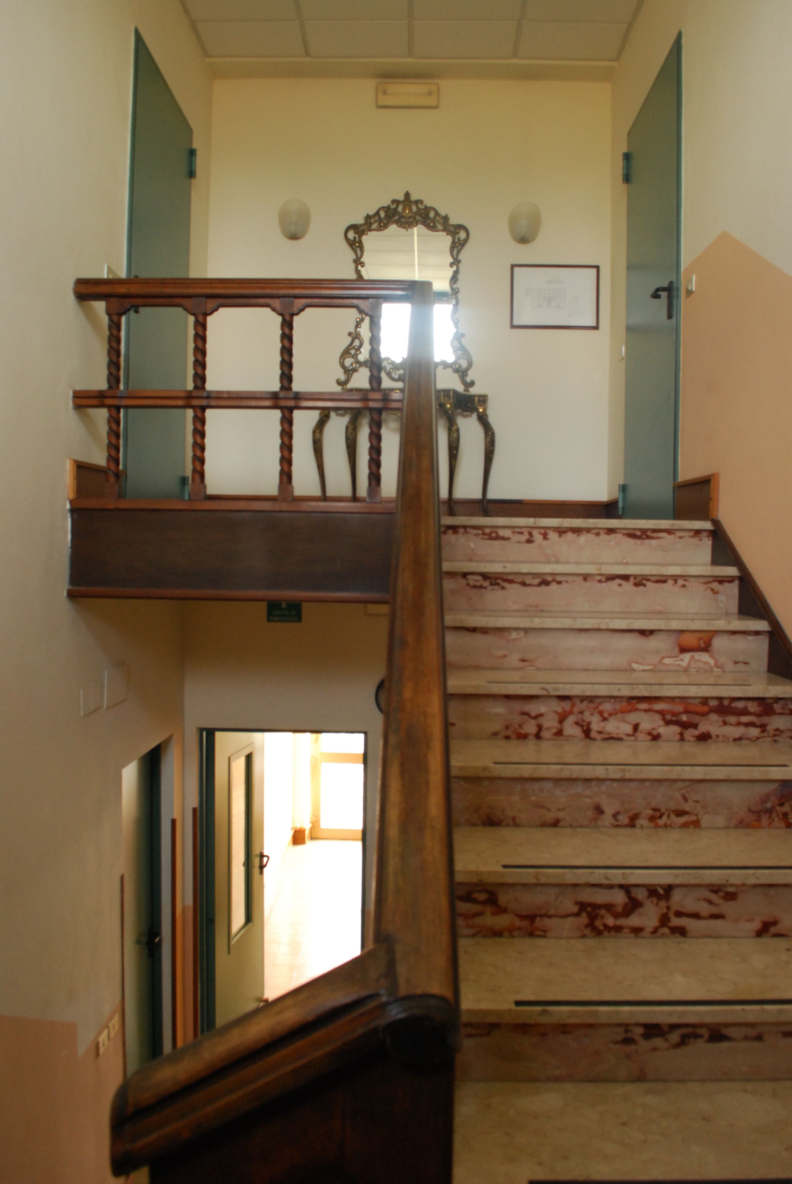 Un escalier avec une rampe en bois et un miroir au-dessus.
