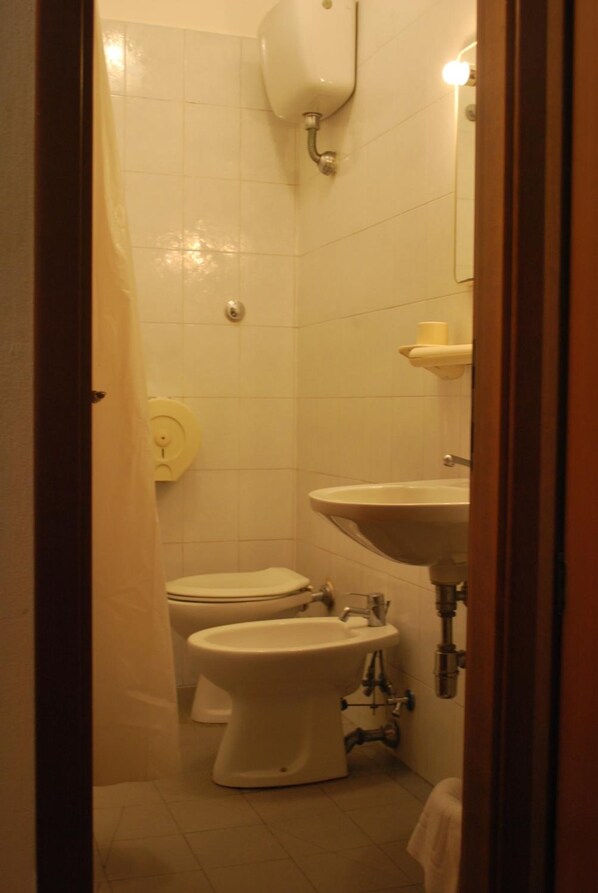 A small bathroom with a toilet, bidet, and sink.