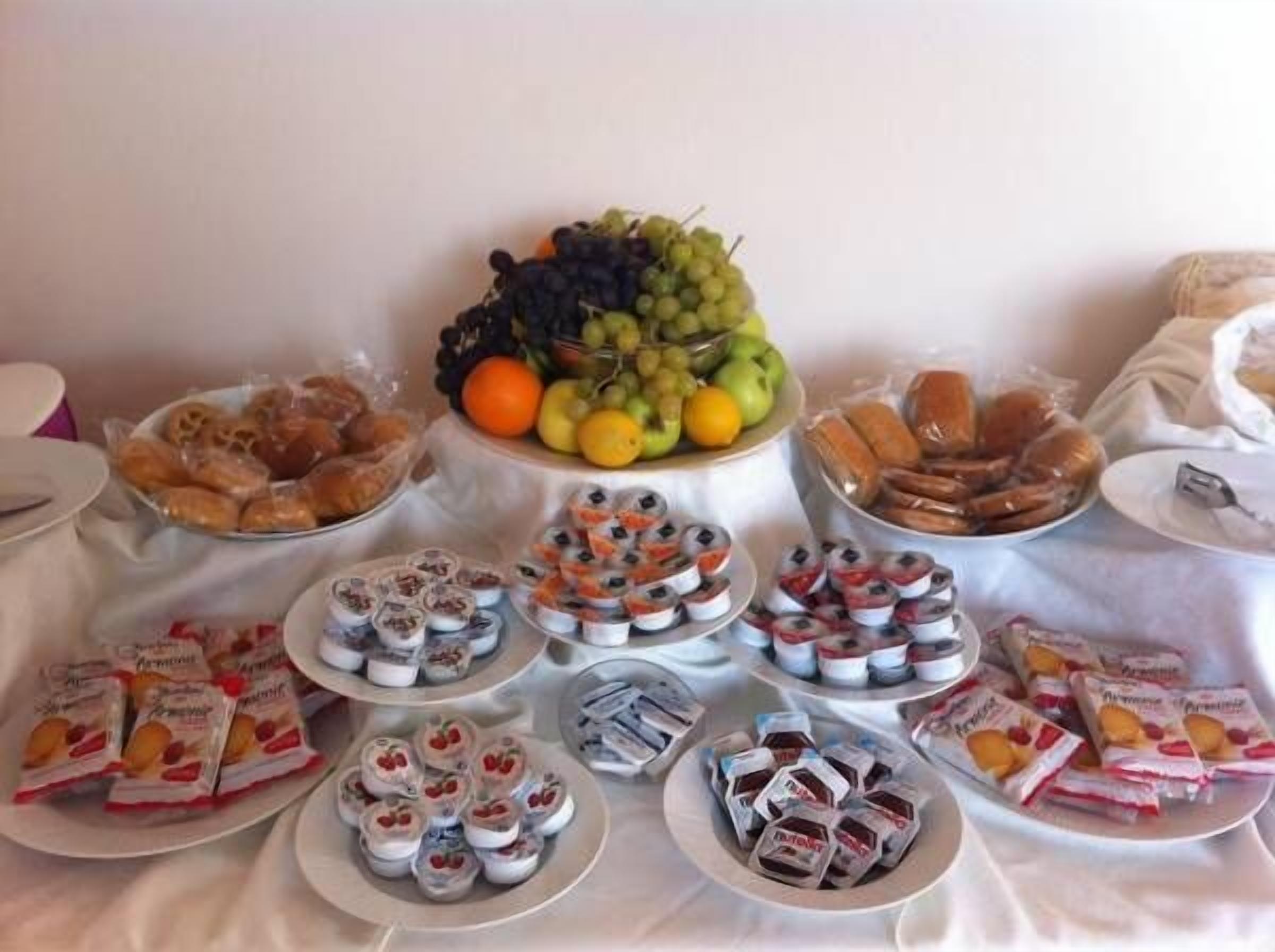 A buffet table with various food items including fruits, pastries, and packaged snacks.