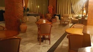 Een hotel lobby met een centraal zithoek, een receptiebalie en een grote zuil.