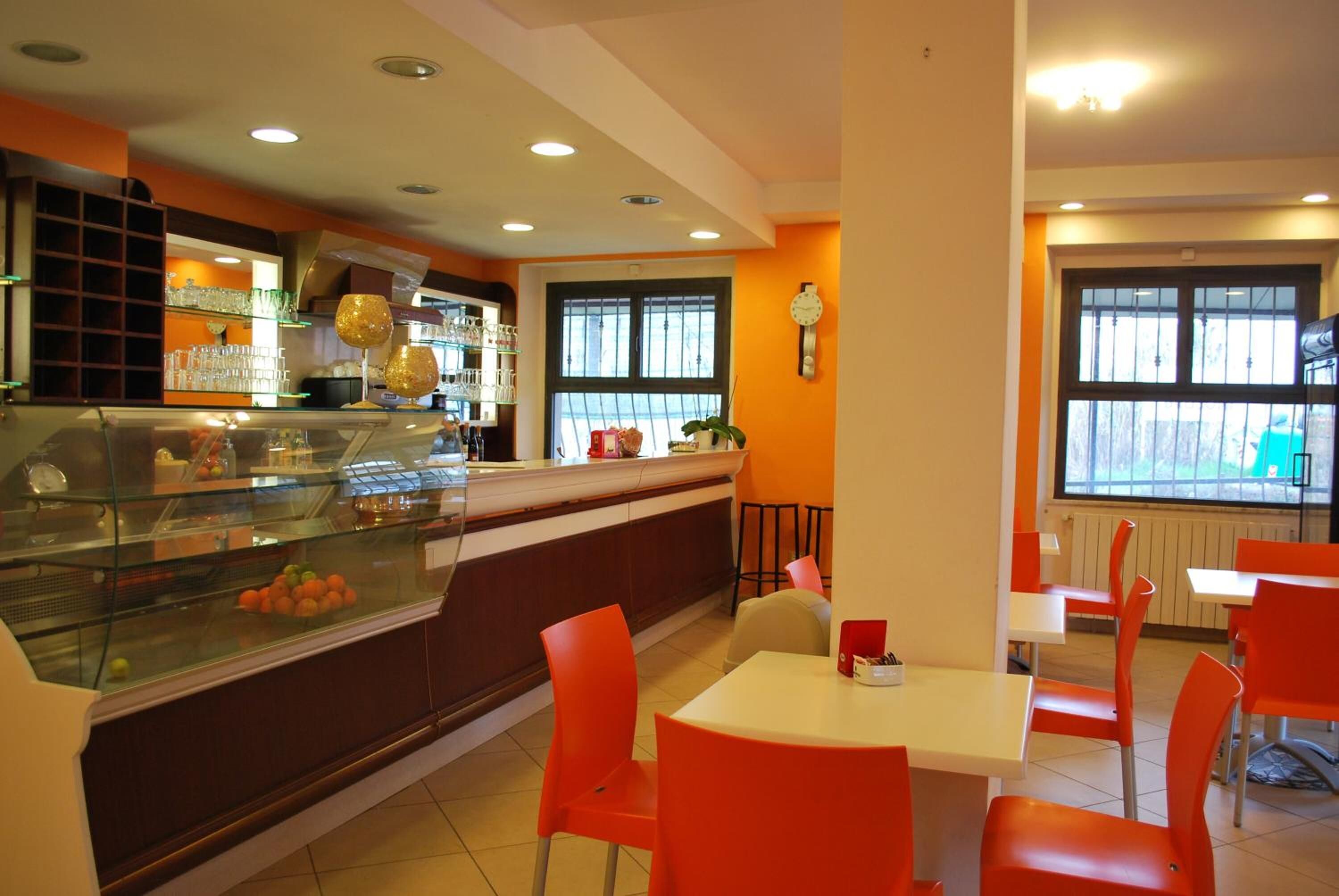 Un ristorante con una teca in vetro, sedie arancioni e una sveglia appesa al muro.