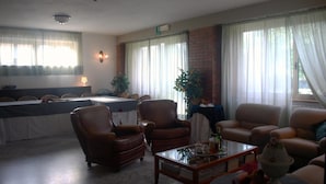 Een ruime woonkamer met een pooltafel, leren fauteuils en een salontafel.