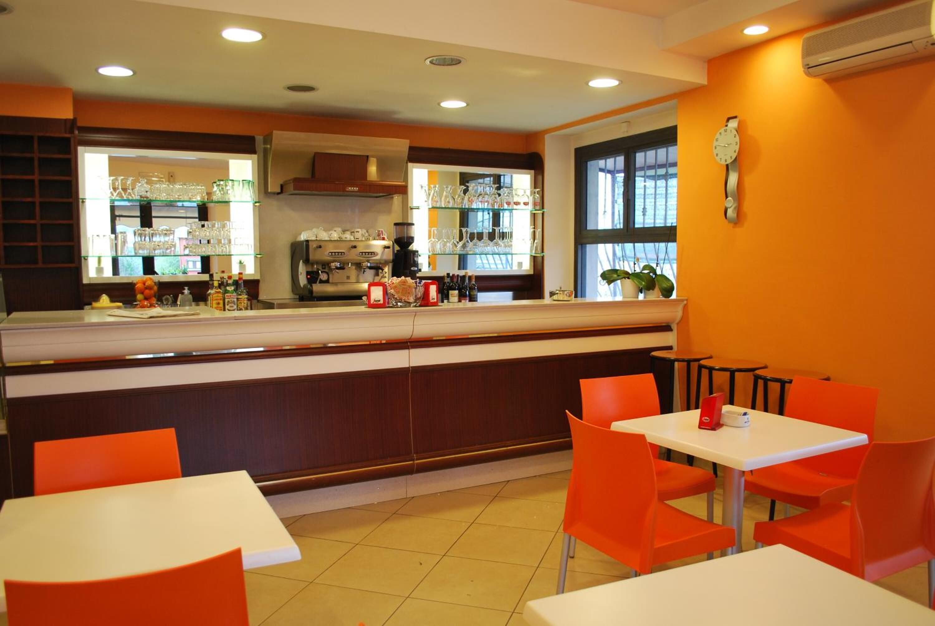 A restaurant with a counter, orange chairs, and a clock on the wall.
