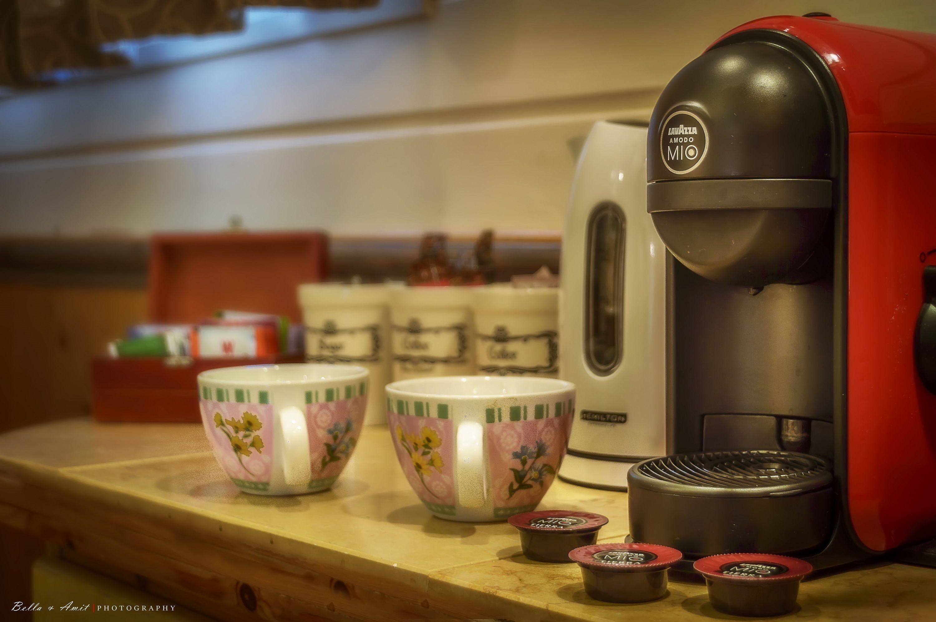 Une machine à café avec deux tasses et des dosettes de café, le tout posé sur une surface en bois.