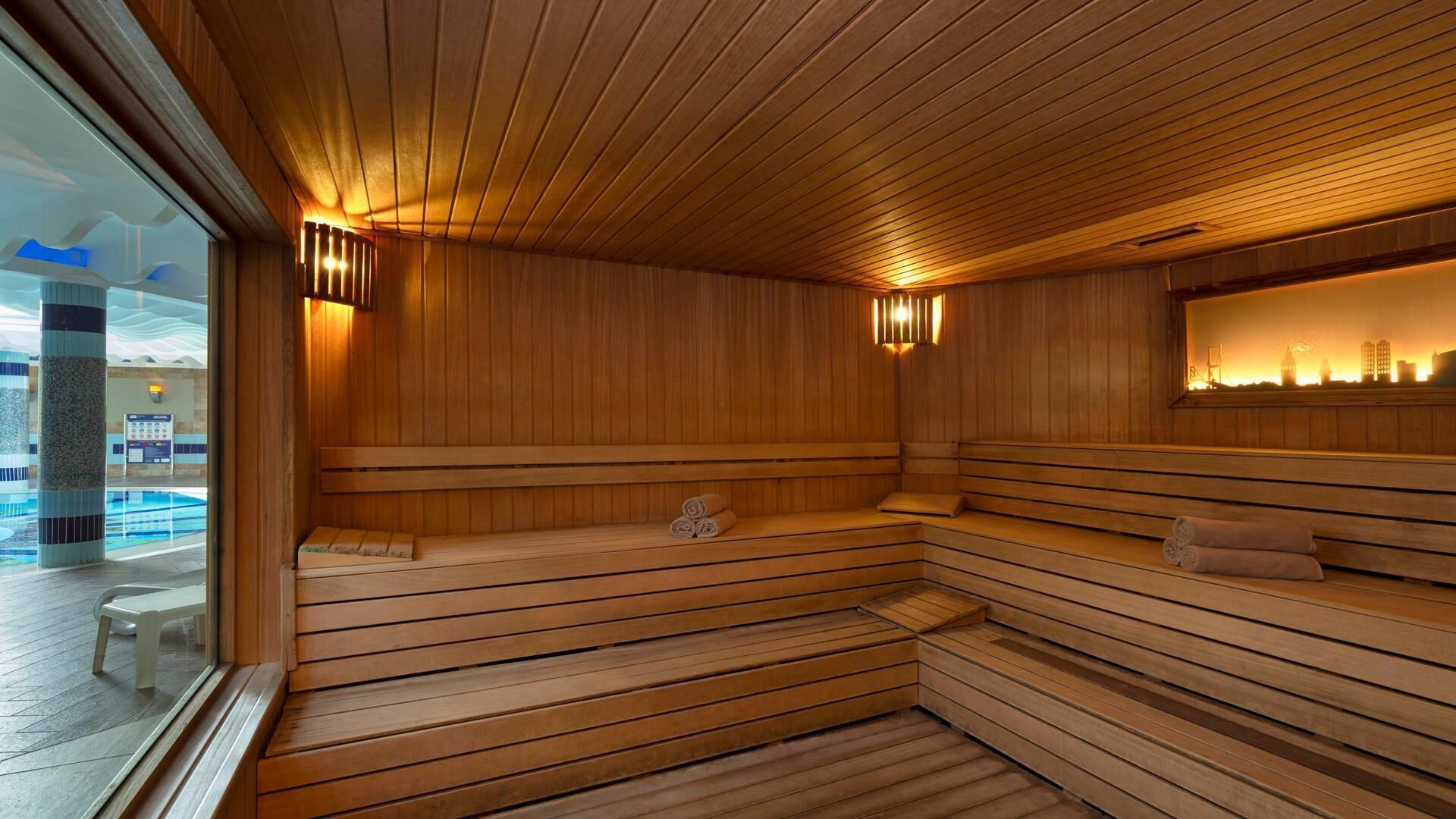 A sauna with wooden benches and a view of a city skyline through a glass wall.