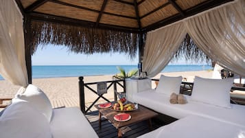 Privat strand, sort sand, solsenger og parasoller