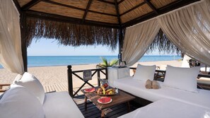 Een privéstrand, zwart zand, ligstoelen aan het strand, parasols