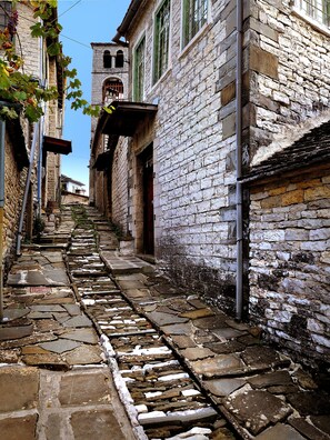A narrow stone pathway leading to a building with a bell tower. - Gaia Guesthouse (Zagori)