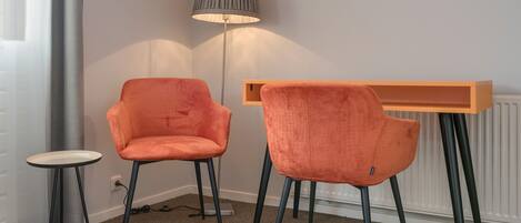 A room with two orange chairs, a small round table, and a floor lamp.