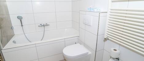 Un baño con bañera, inodoro y perchero para toallas.