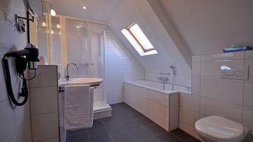 Ein modernes Badezimmer mit Oberlicht, Dusche, Waschbecken und Toilette.