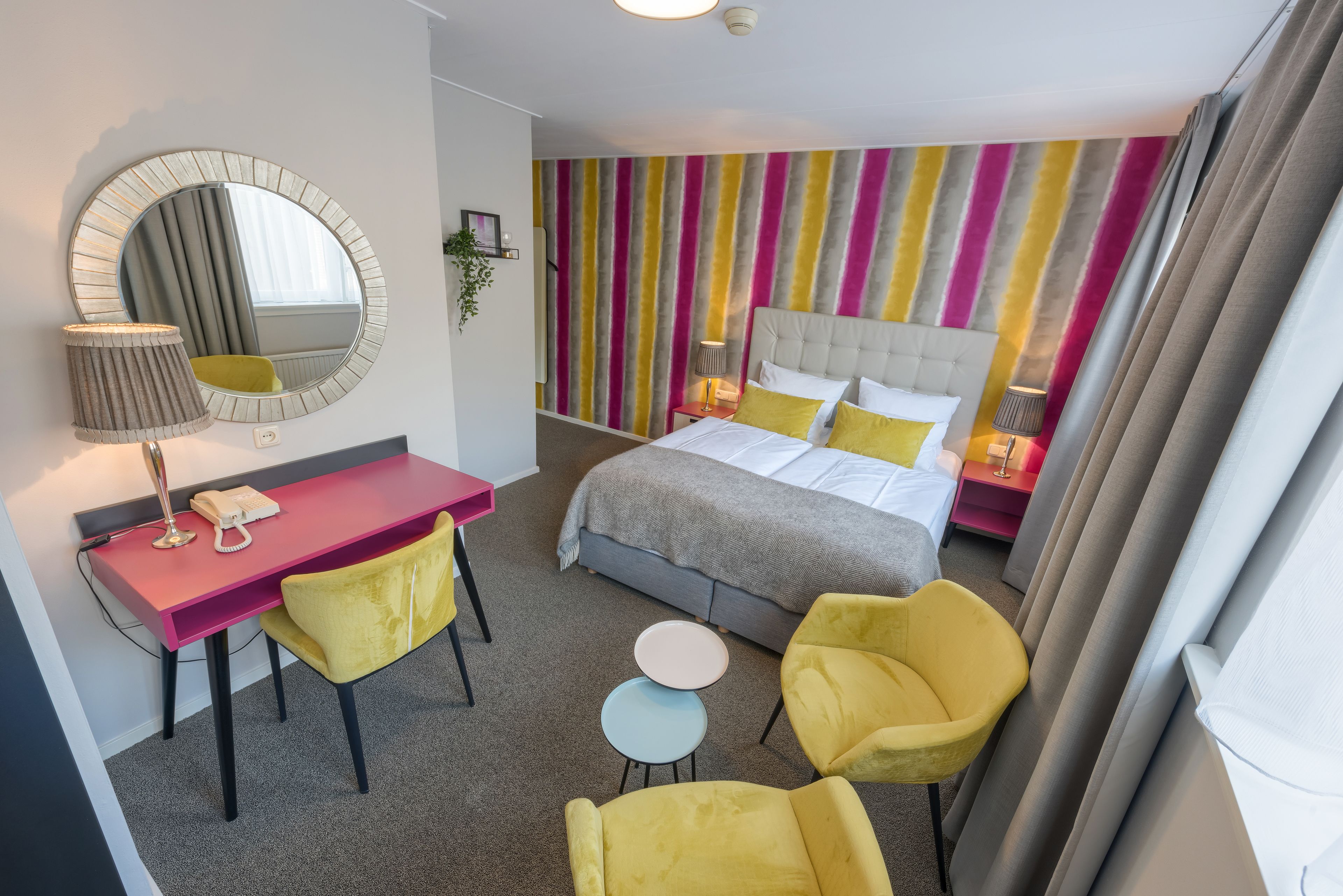 Una habitación de hotel con una cama, un escritorio, dos sillas y una mesita.