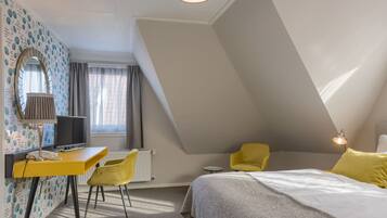 A bedroom with a bed, a desk, a chair, a mirror, and a window with curtains.