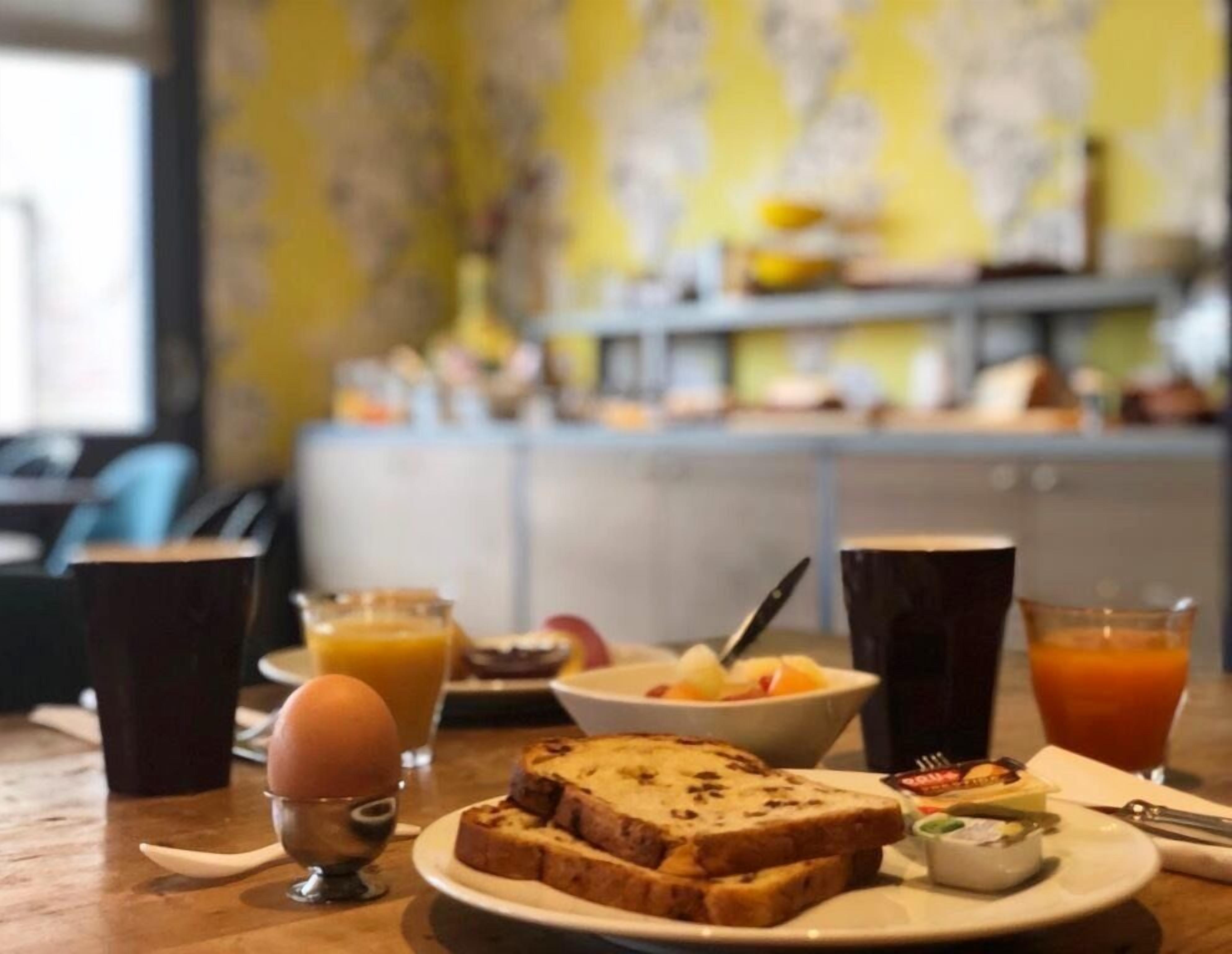 A breakfast table with toast, fruit, a small bowl, and drinks.