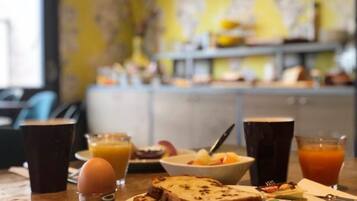 Una mesa de desayuno con tostadas, fruta, un tazón pequeño y bebidas.