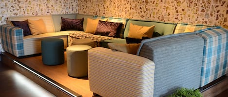 A sectional sofa with multiple cushions, a small ottoman, and a potted plant.