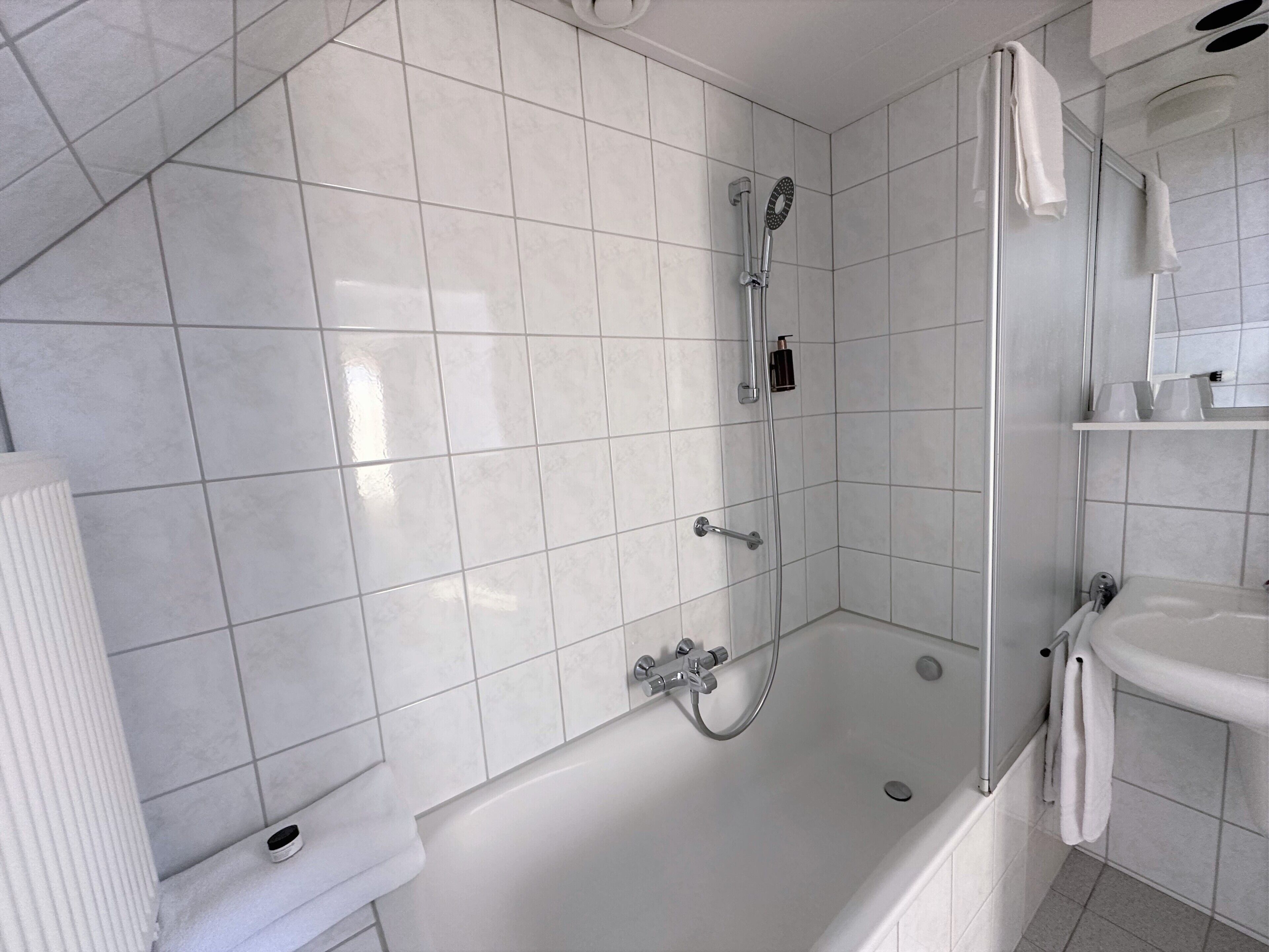 Une salle de bain moderne avec une douche à parois de verre, une baignoire blanche et un lavabo.