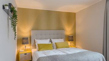 A neatly arranged hotel room with a bed, two bedside tables, and a wall-mounted plant.