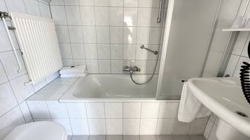 A modern bathroom with a bathtub, shower, toilet, and sink.