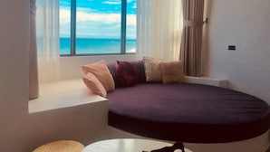 Ein Zimmer mit großem Fenster, einem bogenförmigen Bett und Meerblick.