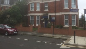 Uma casa geminada de tijolos vermelhos com uma placa azul na fachada.