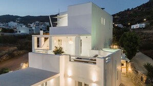 A modern white building with a rooftop terrace, a hot tub, and a stone wall.
