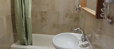 Une salle de bain équipée d’une baignoire, d’un lavabo, de toilettes et d’un rideau de douche.