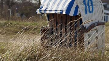 A beach chair with a striped cover and a number '10' on it, surrounded by tall grass.