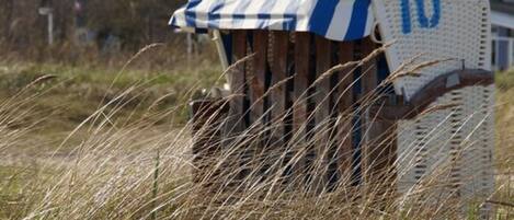 A beach chair with a striped cover and a number '10' on it, surrounded by tall grass.