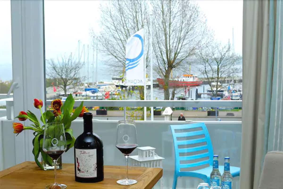 A table with a bottle of wine, a glass of wine, and a vase of tulips.