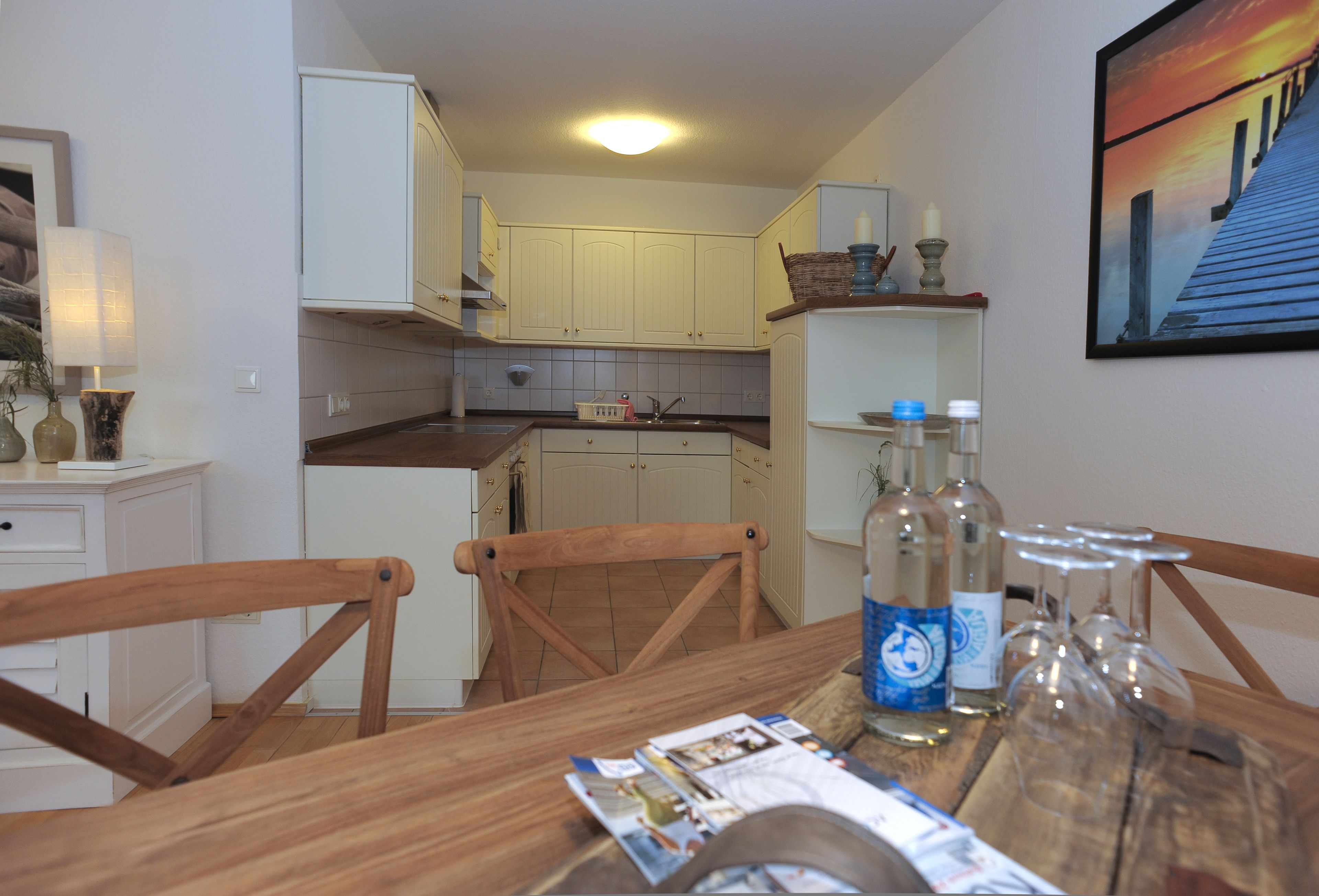 Un coin repas avec une table en bois, des chaises et une cuisine en arrière-plan.