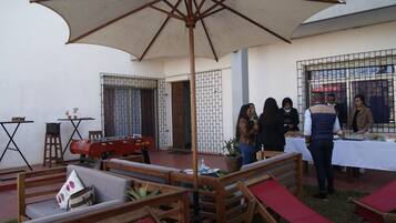 An outdoor patio with wooden furniture, a barbecue grill, and a large umbrella providing shade.