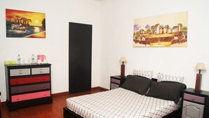 A bedroom with a bed, a dresser, two nightstands, and two wall-mounted lamps. - Villa Mahefa (Antananarivo)