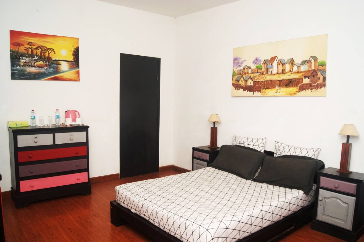 A bedroom with a bed, a dresser, two nightstands, and two wall-mounted lamps.