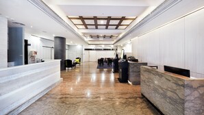 A spacious lobby with a marble floor, a reception desk, and a seating area with chairs and a small table. - CHECK inn Taipei Nanjing (Taipei)