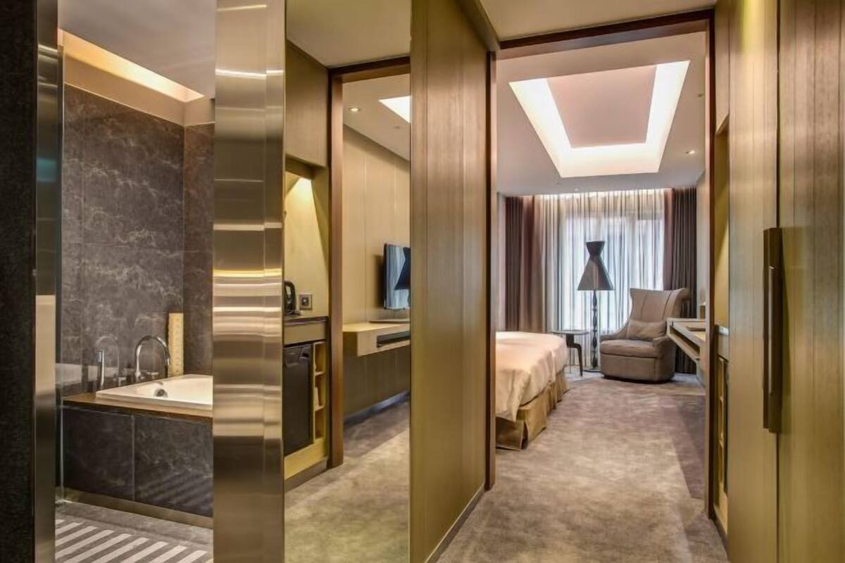 Una habitación de hotel con baño, cama, escritorio y televisor.