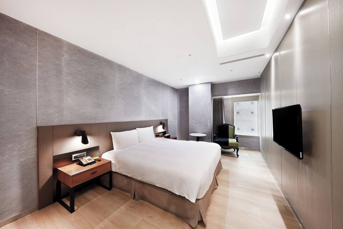 Una habitación de hotel moderna con una cama grande, mesitas de noche, un televisor de pantalla plana y un escritorio.