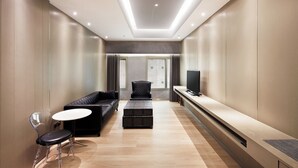 A modern hotel room with a sofa, ottoman, clear chair, and a flat-screen TV. - CHECK inn Taipei Nanjing (Taipei)