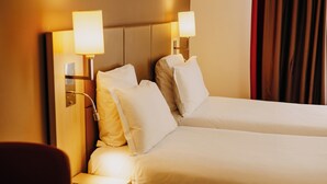 Una habitación de hotel con dos camas, una mesita de noche con una lámpara y un control remoto sobre la mesa auxiliar.