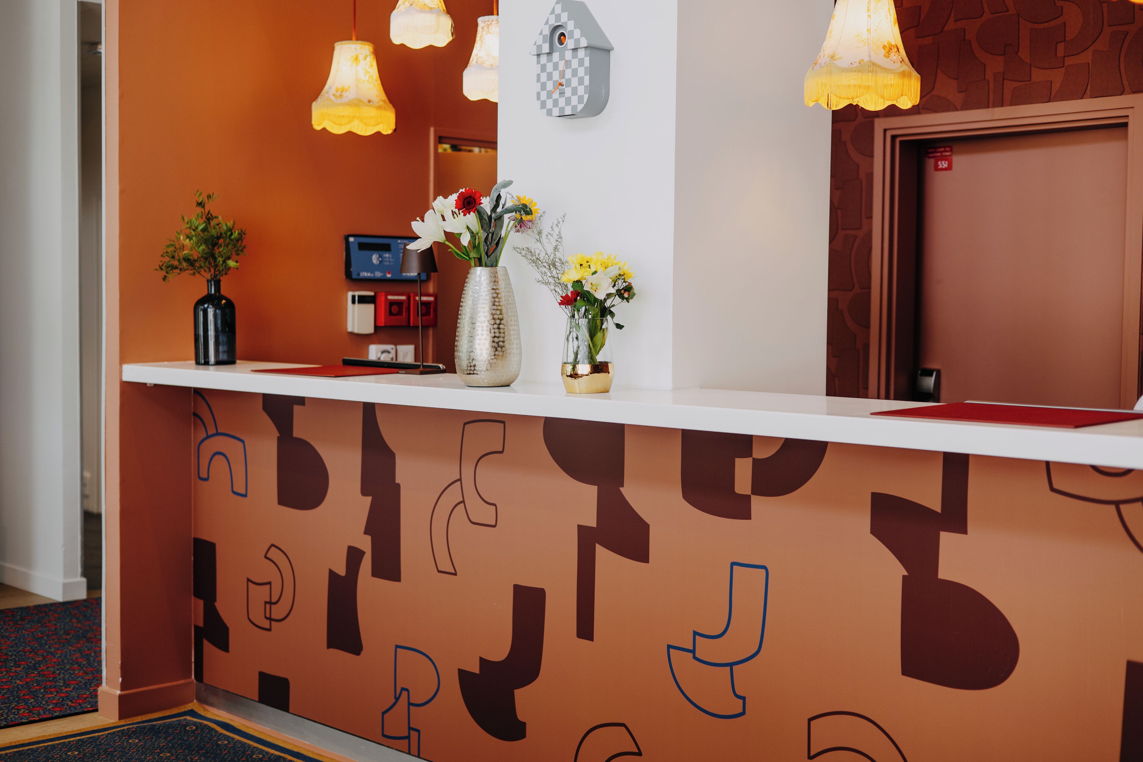 A reception desk with a patterned wall, a check-in counter, and a door.