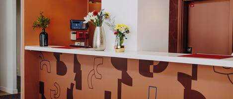 A reception desk with a patterned wall, a check-in counter, and a door.